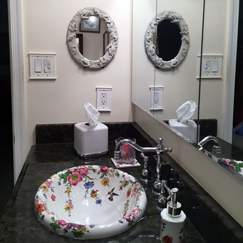 Powder room with black counter and painted flower sink
